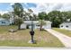 Charming single-story home with well-kept lawn, accented by palm trees and a delightful turquoise door and awnings at 8247 Sw 105Th Pl, Ocala, FL 34481