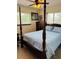 Bedroom with a wooden four-poster bed, dresser, and two large windows at 8547 Sw 106Th Pl, Ocala, FL 34481