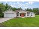 Charming single-story home with a two-car garage, stucco siding, an orange front door and a well-manicured lawn at 144 Malauka Pass, Ocklawaha, FL 32179