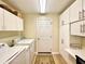 Bright laundry room featuring a washer and dryer, ample cabinet space, and a door leading outside at 15822 Sw 16Th Avenue Rd, Ocala, FL 34473