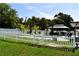Backyard featuring a pool, shaded seating area, palm trees, and a pristine white fence at 2201 Ne 45Th St, Ocala, FL 34479