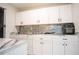Updated kitchenette featuring white cabinetry, black hardware, stylish backsplash, and marble-look countertops at 2563 Coral Ave, Kissimmee, FL 34741