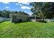 A spacious backyard with a white fence, lush green lawn, screened in back porch, mature trees, and access door at 26 Hemlock Terrace Dr, Ocala, FL 34472