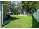 A spacious backyard with a white fence, green lawn, and screened in back porch at 26 Hemlock Terrace Dr, Ocala, FL 34472