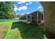 A spacious backyard with a white fence, lush green lawn, screened in back porch, and mature trees at 26 Hemlock Terrace Dr, Ocala, FL 34472