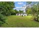 A grassy backyard surrounds this white home with a red door and charcoal grill at 2602 Ne 2Nd Ave, Ocala, FL 34470