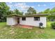 The backyard features a red door, a white stucco exterior, grill, and green grass at 2602 Ne 2Nd Ave, Ocala, FL 34470