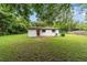 A white stucco home has a red door, charcoal grill, and a big grassy backyard at 2602 Ne 2Nd Ave, Ocala, FL 34470