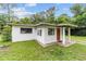 Charming single-story home featuring a red door, stucco siding, and a well-maintained front lawn at 2602 Ne 2Nd Ave, Ocala, FL 34470