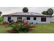 Rear view of house featuring a lawn with shrubs and flowers, solar panels, and dark framed windows at 313 Oak Track Trce, Ocala, FL 34472