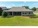 The back exterior showcases a screened-in porch, manicured lawn, and mature shrubbery at 5093 Nw 35Th Lane Rd, Ocala, FL 34482