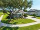 Front yard of a gray home featuring a large tree, well-manicured landscaping, and a circular driveway at 5093 Nw 35Th Lane Rd, Ocala, FL 34482