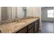 Bathroom featuring double vanity with granite counters, framed mirror and wood look flooring at 6865 Sw 153 Place Rd, Ocala, FL 34473