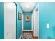Hallway with bright turquoise walls, white trim, wood floors, and western-themed artwork at 7242 Sw 115Th Pl, Ocala, FL 34476