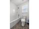 Bathroom featuring white toilet, bathtub, gray tile floors and a window at 7695 Sw 64Th Street Rd, Ocala, FL 34474