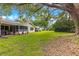 Expansive backyard with lush green grass, mature trees, and a screened-in porch attached to the home at 8850 Sw 97Th St # C, Ocala, FL 34481