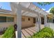 Covered patio area with tiled floor, white pergola, and lush landscaping at 8881 Sw 94Th St # E, Ocala, FL 34481