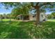 A home and a spacious, grassy backyard beneath a large tree at 8973 Sw 104Th Pl, Ocala, FL 34481