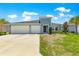 Charming light blue home boasting a well-manicured lawn and a spacious three-car garage, under a bright blue sky at 9209 Sw 58Th Cir, Ocala, FL 34476