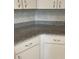 Close up of gray granite counter, white tile backsplash and white cabinets in a kitchen at 9711 Sw 97Th Pl, Ocala, FL 34481