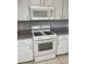 Close-up of white gas range oven and microwave in a kitchen with tile flooring at 9711 Sw 97Th Pl, Ocala, FL 34481