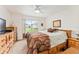 Comfortable bedroom with a ceiling fan, two dressers, a bed, and a view of the exterior at 13100 Se 93Rd Terrace Rd, Summerfield, FL 34491