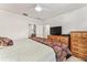 Comfortable bedroom features a ceiling fan, a dresser with TV and a bed with patterned coverlet at 13100 Se 93Rd Terrace Rd, Summerfield, FL 34491