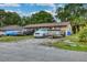 A single-story home has a beige exterior with a variety of cars and trucks parked in the yard at 2508 India Palm Dr, Edgewater, FL 32141
