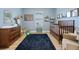 Bedroom featuring blue walls, wood-look floors, area rug, and a wood crib at 2984 Ne 43Rd Rd, Ocala, FL 34470