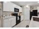 Kitchen features white cabinets, black appliances, grey countertops, and tile floors at 2984 Ne 43Rd Rd, Ocala, FL 34470