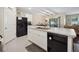Kitchen island boasts a sink and dishwasher, with white cabinets and tile flooring at 2984 Ne 43Rd Rd, Ocala, FL 34470