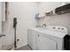 Bright laundry area featuring a washer, dryer, overhead shelf, and gray tile flooring at 2984 Ne 43Rd Rd, Ocala, FL 34470