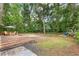Large backyard with a wooden deck, fire pit area, and lush greenery at 3640 Se 131St Ln, Belleview, FL 34420