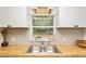 Close-up of a kitchen featuring stainless steel sink, butcher block countertops, and a window at 3640 Se 131St Ln, Belleview, FL 34420