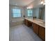 Bright bathroom featuring double vanity, a garden tub, tile flooring, and natural light from grid windows at 3650 Se 55Th Ct, Ocala, FL 34480