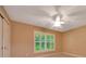 Bedroom showcases a ceiling fan, large window with shutters, and tan carpeting at 3769 Grove View Ln, Port Orange, FL 32129