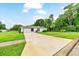 Spacious driveway leading to a well-maintained home with a two-car garage, surrounded by green lawns and trees at 3769 Grove View Ln, Port Orange, FL 32129