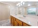 Bright bathroom featuring dual sinks, wooden cabinets, and a large vanity mirror at 4360 Se 106Th St, Belleview, FL 34420