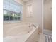 Bathroom featuring a marble-trimmed soaking tub, large window, and a neutral color palette at 4360 Se 106Th St, Belleview, FL 34420