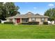 Charming single-story home featuring well-manicured lawn, lush landscaping, and inviting red front door at 4360 Se 106Th St, Belleview, FL 34420