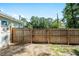 Backyard view featuring a wooden fence with a gate, surrounded by lush greenery and clear blue skies at 5740 Nw 61St St, Ocala, FL 34482
