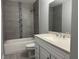 Modern bathroom with gray tiled shower, white vanity, and granite countertop at 6422 Nw 62Nd Pl, Ocala, FL 34482