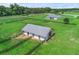 Overhead view of horse barn, surrounded by green pasture, and wood perimeter fencing on horse property at 7041 Ne 22Nd Court Rd, Ocala, FL 34479
