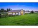 This barn features a white exterior, grey roof, and is surrounded by lush, green grass and black fencing at 7041 Ne 22Nd Court Rd, Ocala, FL 34479