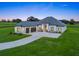Expansive home featuring a modern design, well-lit exterior, and a long private driveway on lush green grounds at 7041 Ne 22Nd Court Rd, Ocala, FL 34479