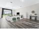 Spacious living room with wood flooring, a large white sectional, and view of the fenced-in pasture at 7041 Ne 22Nd Court Rd, Ocala, FL 34479
