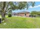 Backyard with a screened-in lanai, mature tree providing shade, and fenced perimeter of the property at 7220 Nw 83 Ter, Ocala, FL 34482