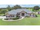 Landscaped front yard showcasing a lush lawn, mature plantings, and a one-story home with stone accents at 7220 Nw 83 Ter, Ocala, FL 34482