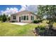 Back of the house featuring green grass, a patio, lush plantings, and a neutral stucco exterior at 7765 Sw 86Th Loop, Ocala, FL 34476