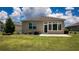 Back of the house featuring green grass, a patio, lush plantings, and a neutral stucco exterior at 7765 Sw 86Th Loop, Ocala, FL 34476